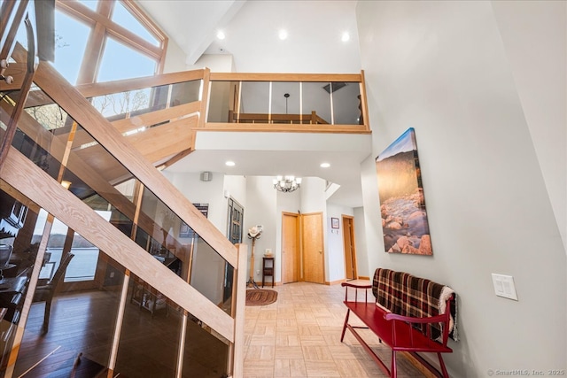 interior space with an inviting chandelier, high vaulted ceiling, baseboards, beamed ceiling, and stairway