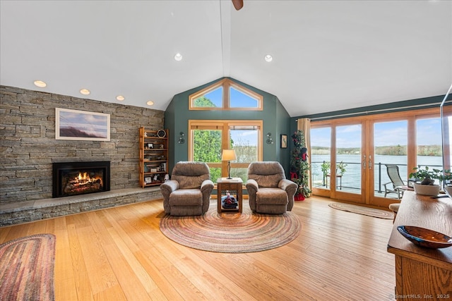 living area featuring a fireplace, wood-type flooring, recessed lighting, lofted ceiling, and a water view