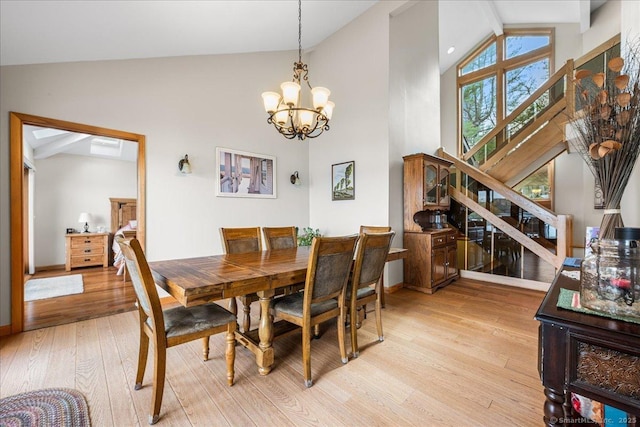 dining area featuring stairway, high vaulted ceiling, baseboards, a chandelier, and light wood-style floors