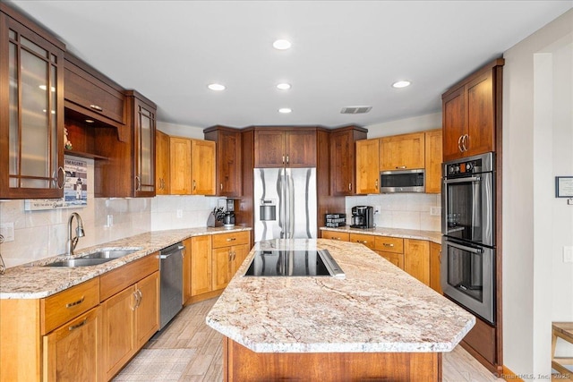 kitchen featuring visible vents, a center island, a sink, light wood-style floors, and stainless steel appliances