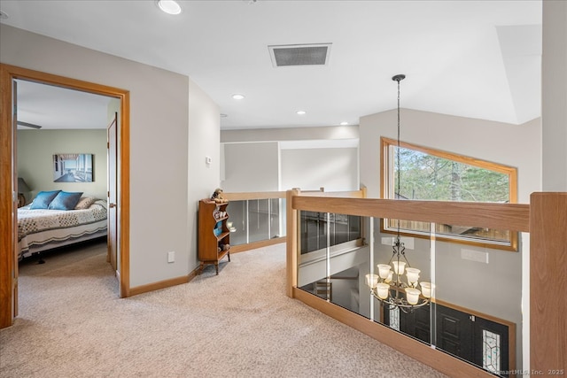 hallway featuring visible vents, baseboards, carpet flooring, a notable chandelier, and an upstairs landing