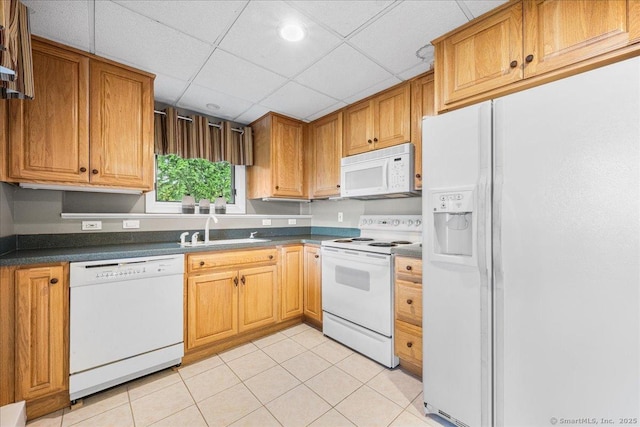 kitchen featuring dark countertops, white appliances, a paneled ceiling, a sink, and light tile patterned floors