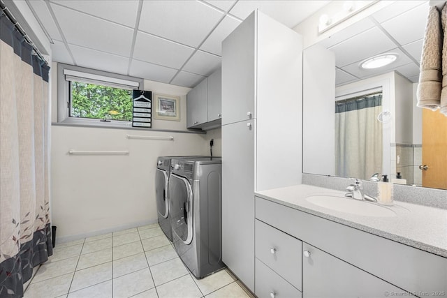 clothes washing area with laundry area, washer and dryer, baseboards, a sink, and light tile patterned floors