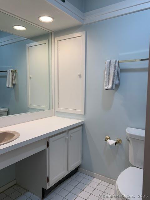 half bath featuring tile patterned flooring, vanity, toilet, recessed lighting, and baseboards