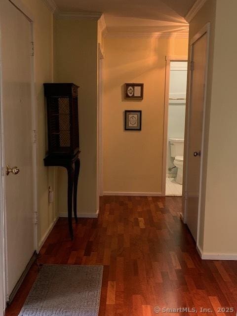 corridor featuring crown molding, baseboards, and wood finished floors