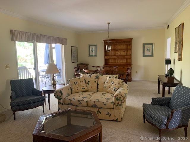 living area with light colored carpet, ornamental molding, and baseboards