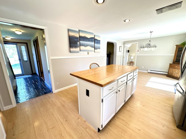 kitchen featuring wooden counters, white cabinetry, arched walkways, a baseboard radiator, and a notable chandelier