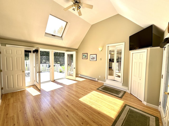 interior space with lofted ceiling with skylight, ceiling fan, light wood-type flooring, french doors, and a baseboard radiator