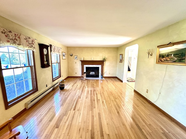 unfurnished living room featuring light wood-type flooring, a fireplace with flush hearth, baseboards, and a baseboard heating unit