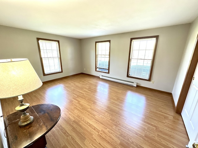 living area with light wood-style floors, baseboards, and baseboard heating