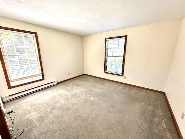 empty room with carpet flooring, baseboards, and a baseboard heating unit
