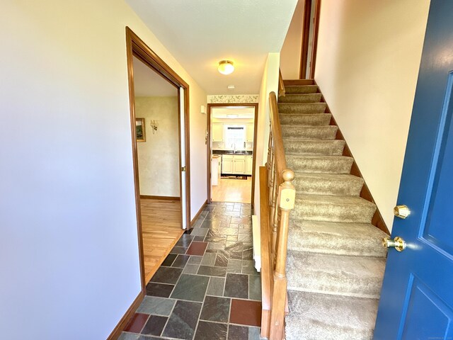 stairway featuring baseboards and stone tile flooring
