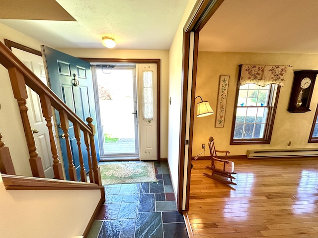 foyer featuring baseboards, a baseboard heating unit, hardwood / wood-style floors, and stairway