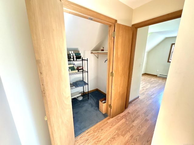 interior space with wood finished floors, a baseboard heating unit, and vaulted ceiling