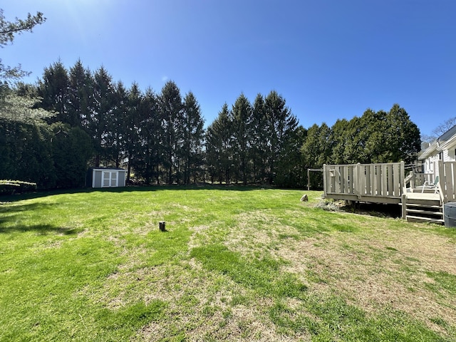 view of yard featuring an outdoor structure, a shed, and a deck