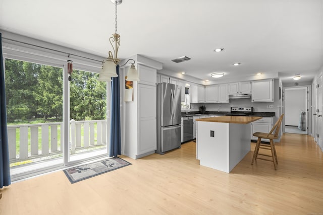 3 Eastwood Dr, Granby, CT 06060 - kitchen with stainless steel appliances, under cabinet range hood, light wood-type flooring, a sink, and a kitchen bar
