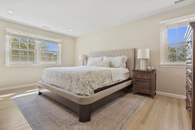 bedroom featuring baseboards, multiple windows, and light wood-style flooring