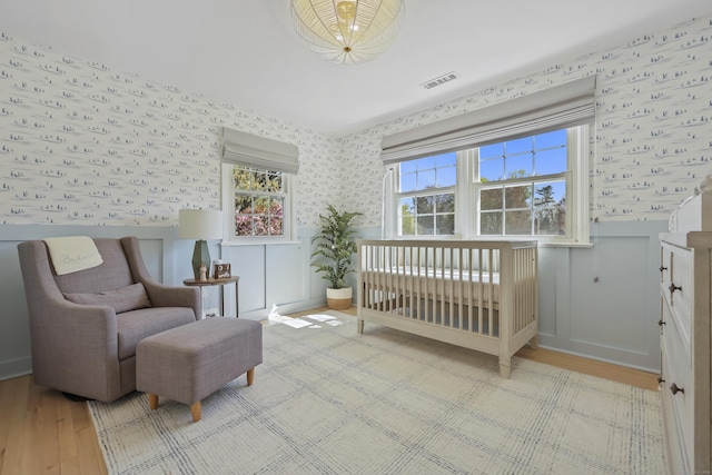 bedroom with visible vents, wood finished floors, and wallpapered walls
