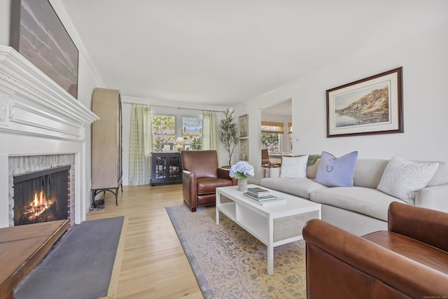 living room featuring crown molding, light wood-style flooring, and a fireplace