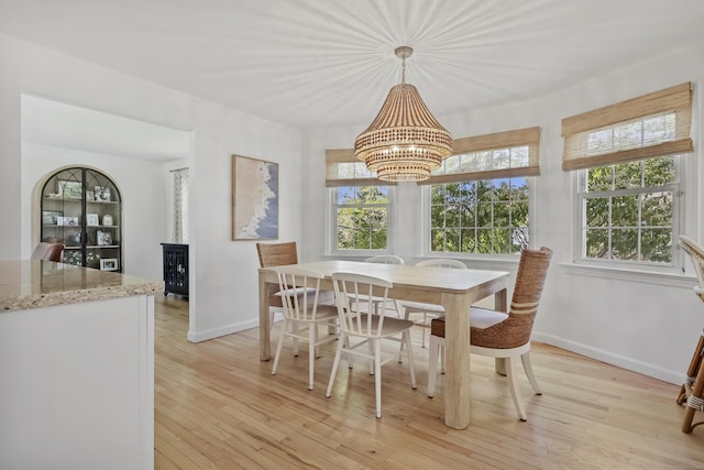 dining space with light wood-style floors, baseboards, a notable chandelier, and a wealth of natural light