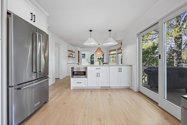 kitchen featuring a peninsula, white cabinetry, high end refrigerator, light wood finished floors, and decorative light fixtures
