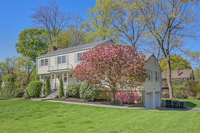 view of front of house featuring a garage, a balcony, a front yard, a chimney, and a porch