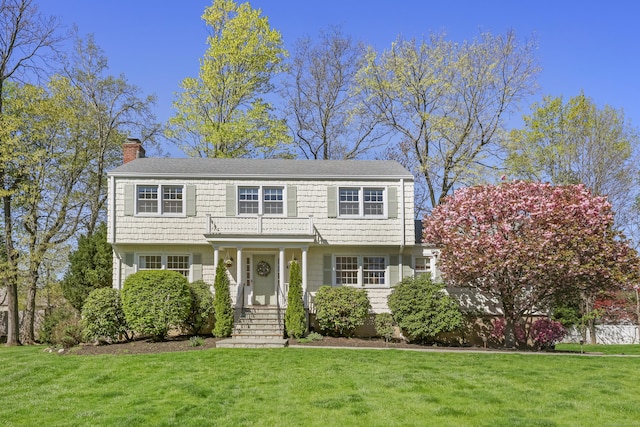 colonial-style house with a front lawn and a chimney