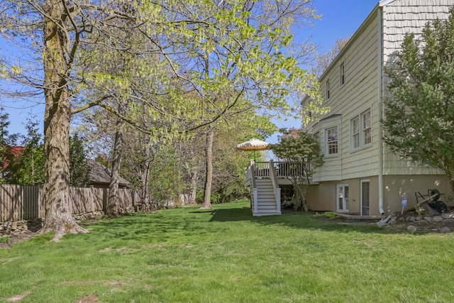 view of yard with fence, a wooden deck, and stairway