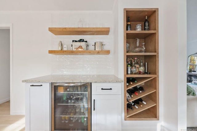 bar with ornamental molding, beverage cooler, light wood-type flooring, a dry bar, and backsplash