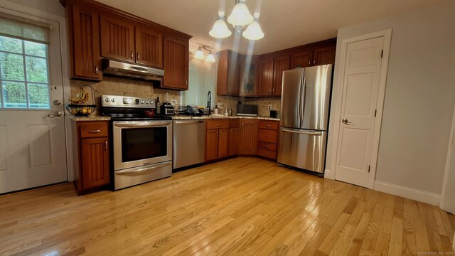 283 Hillcrest Ave, Newington, CT 06111 - kitchen with stainless steel appliances, under cabinet range hood, light wood-style flooring, tasteful backsplash, and a chandelier