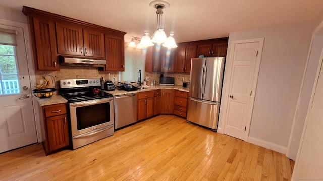 283 Hillcrest Ave, Newington, CT 06111 - kitchen featuring appliances with stainless steel finishes, under cabinet range hood, backsplash, light wood finished floors, and a chandelier