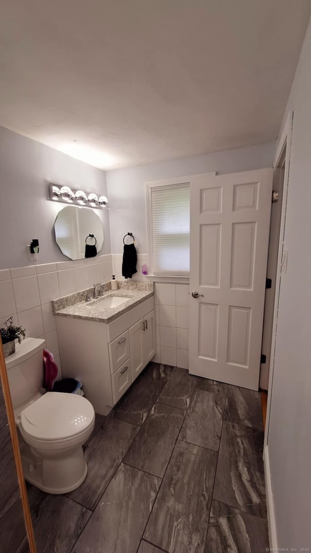283 Hillcrest Ave, Newington, CT 06111 - bathroom with tile walls, vanity, toilet, wainscoting, and marble look tile flooring