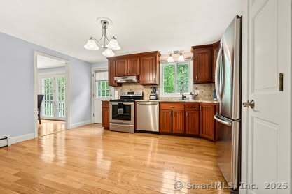 283 Hillcrest Ave, Newington, CT 06111 - kitchen with stainless steel appliances, under cabinet range hood, plenty of natural light, and a chandelier
