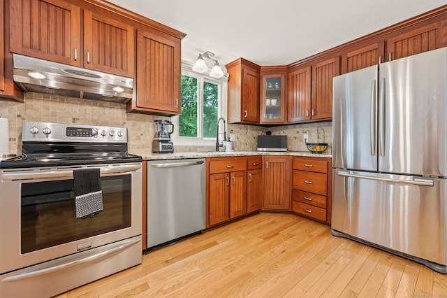 283 Hillcrest Ave, Newington, CT 06111 - kitchen with appliances with stainless steel finishes, under cabinet range hood, a sink, light wood-type flooring, and brown cabinets