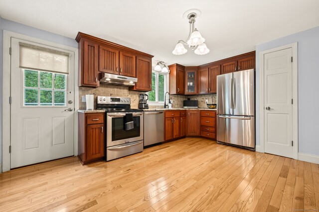 283 Hillcrest Ave, Newington, CT 06111 - kitchen with appliances with stainless steel finishes, under cabinet range hood, a chandelier, light wood-style floors, and decorative backsplash
