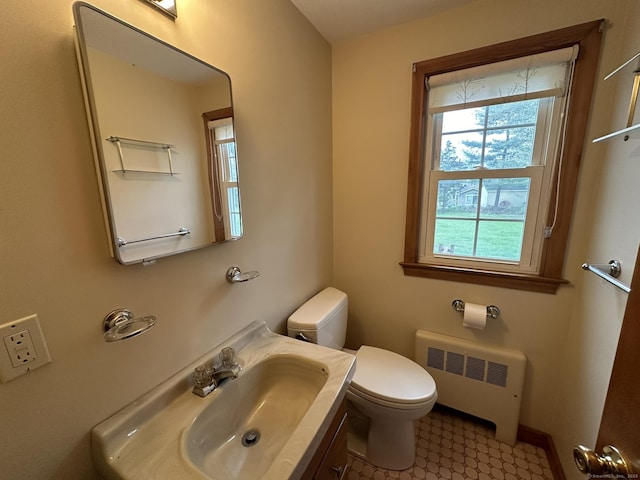 bathroom with radiator, baseboards, vanity, and toilet