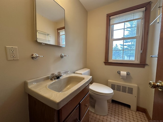 half bathroom featuring toilet, a wealth of natural light, radiator heating unit, and vanity