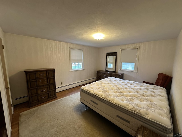 bedroom featuring baseboard heating and wood finished floors