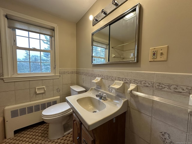 bathroom with vanity, radiator, toilet, tile walls, and a wainscoted wall