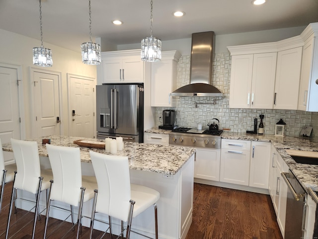 kitchen with wall chimney range hood, backsplash, dark wood-style flooring, appliances with stainless steel finishes, and white cabinetry