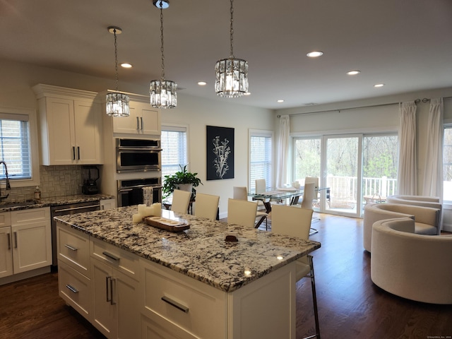 kitchen featuring white cabinets, a sink, recessed lighting, dark wood-type flooring, and a kitchen island