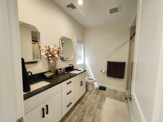 bathroom featuring toilet, visible vents, a sink, and wood finished floors