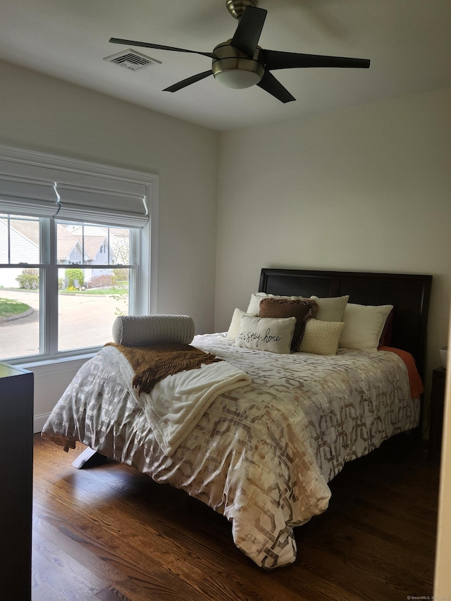bedroom with a ceiling fan, visible vents, and wood finished floors