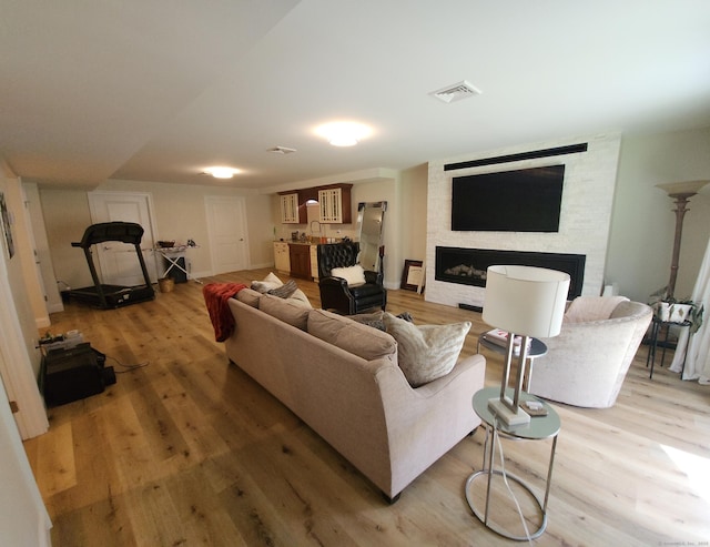 living room with visible vents, a fireplace, and light wood-type flooring