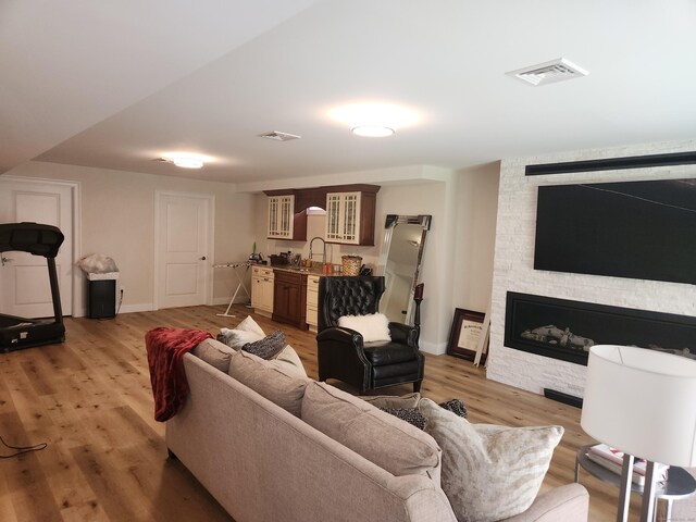 living room featuring baseboards, a fireplace, light wood-type flooring, and visible vents