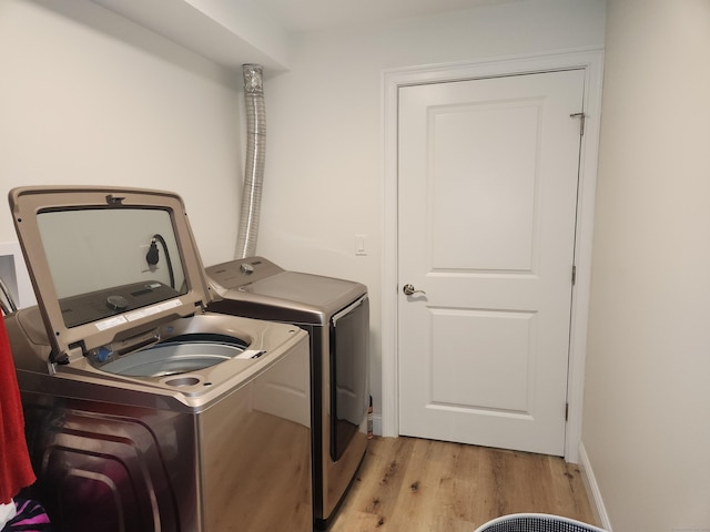 washroom featuring laundry area, washer and clothes dryer, and light wood finished floors