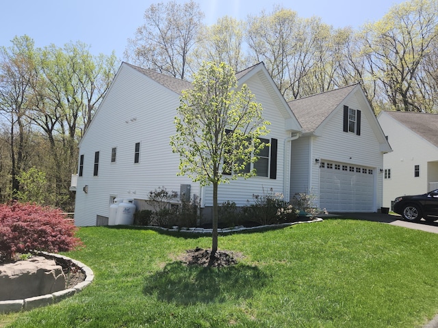 view of front of house featuring roof with shingles, a front yard, and aphalt driveway