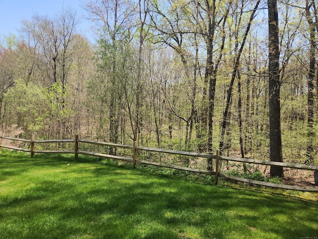view of yard featuring fence and a wooded view