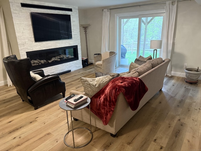 living area with baseboards, a fireplace, and wood finished floors