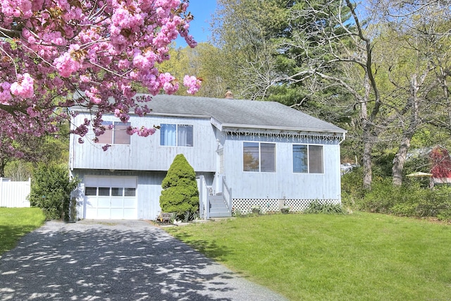 view of front facade with a garage, driveway, a front yard, and a shingled roof